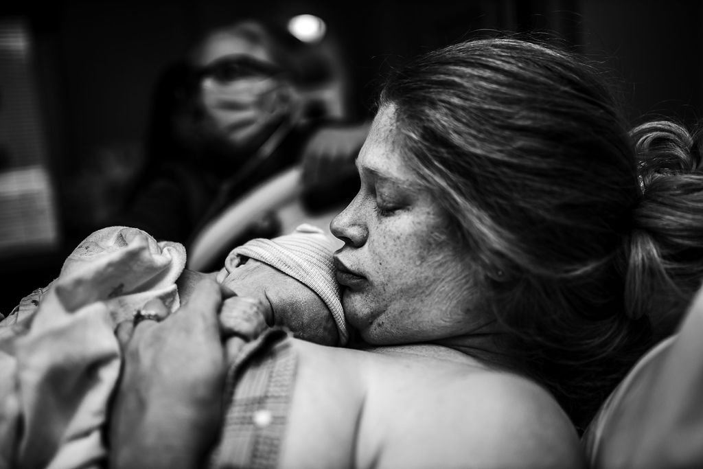 Mother holding her newborn moments after birth during a DFW birth photography session.