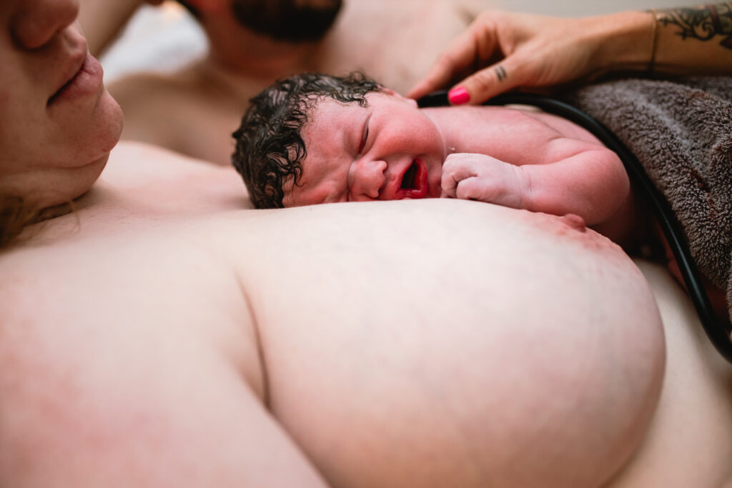 Newborn baby placed on mother’s chest moments after birth during a Fort Worth home birth, documented by a birth photographer.