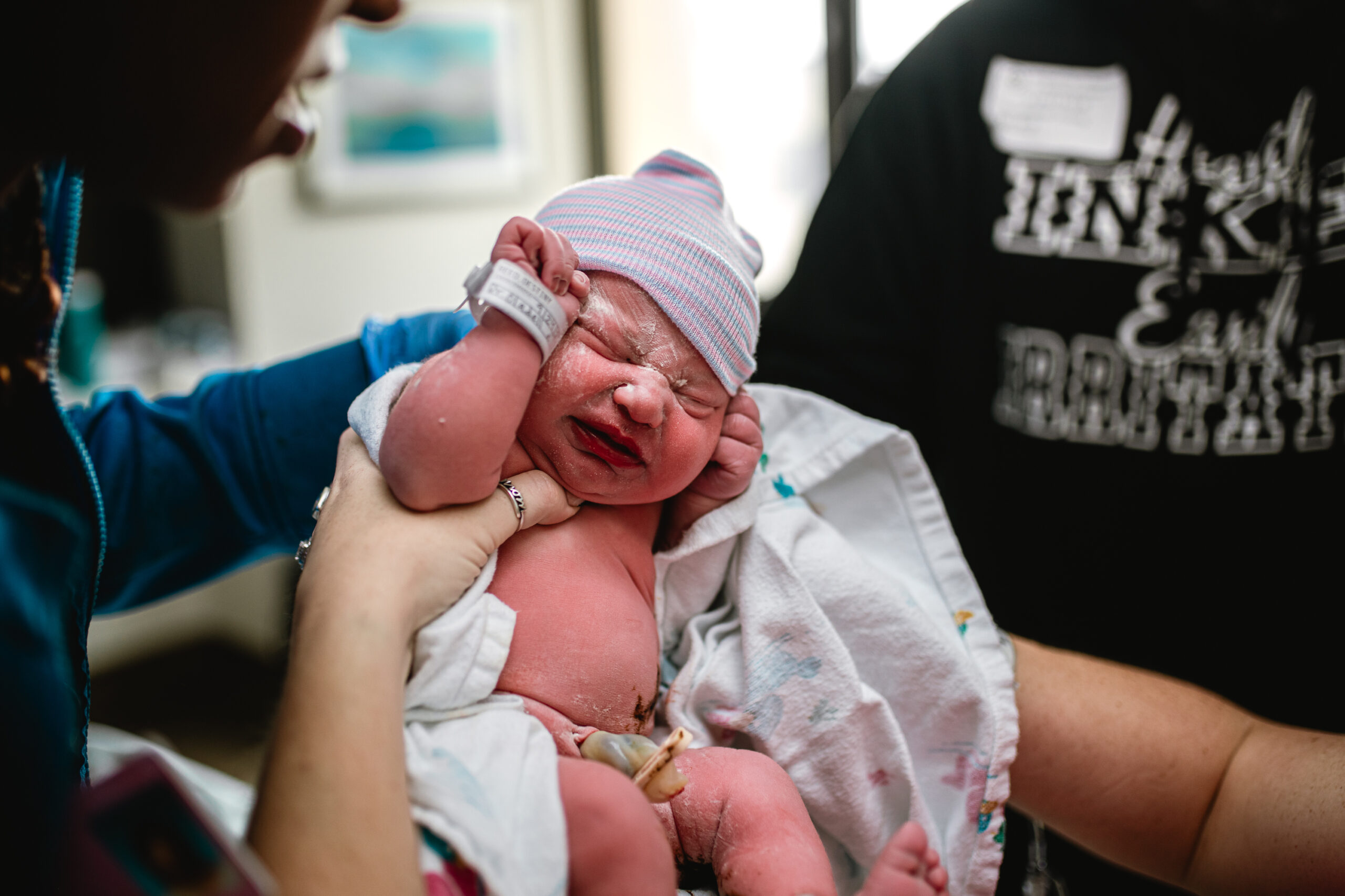 Fort Worth birth photographer capturing a newborn’s first moments as baby is lifted into parents’ arms during a hospital birth.