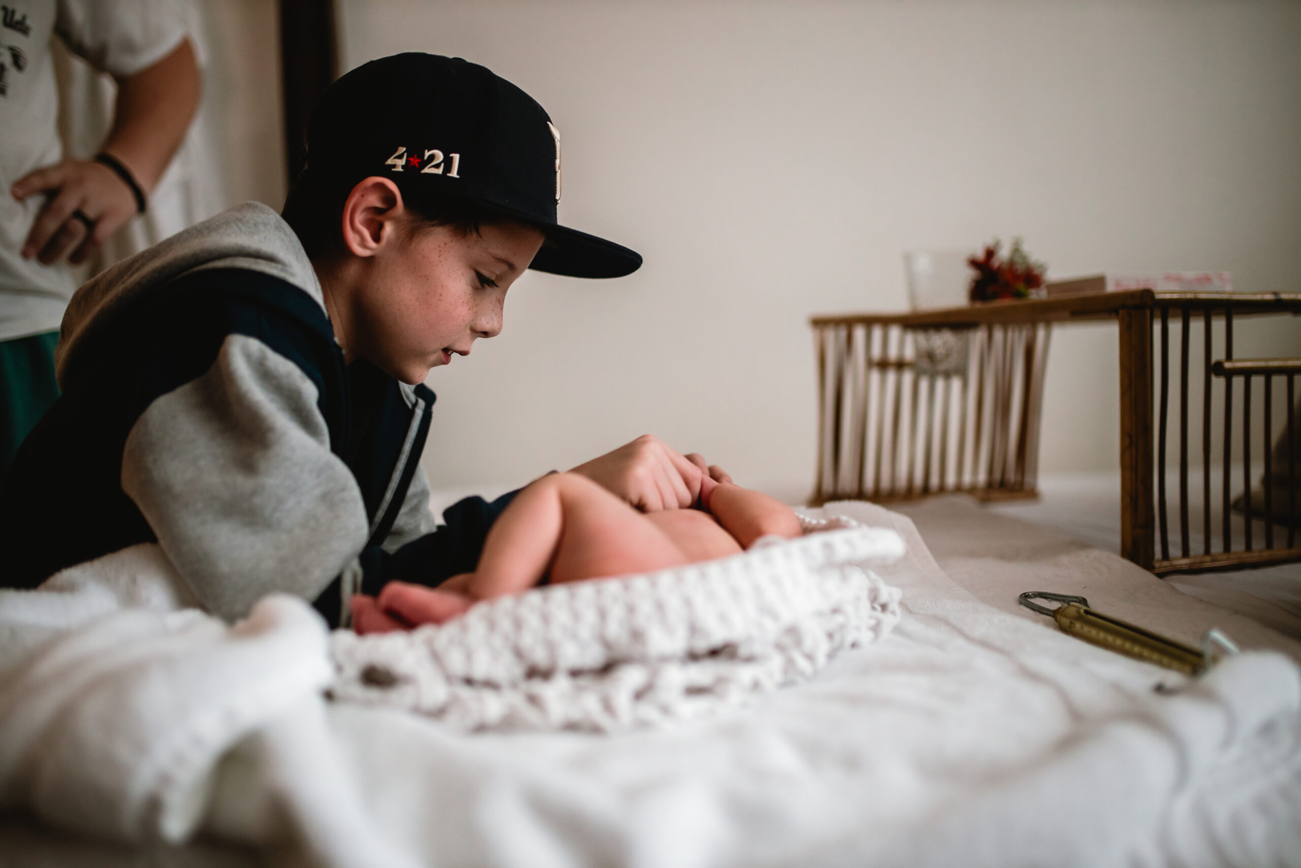 Big brother seeing his newborn sibling for the first time after birth in Fort Worth, documented in a gentle storytelling photography style.