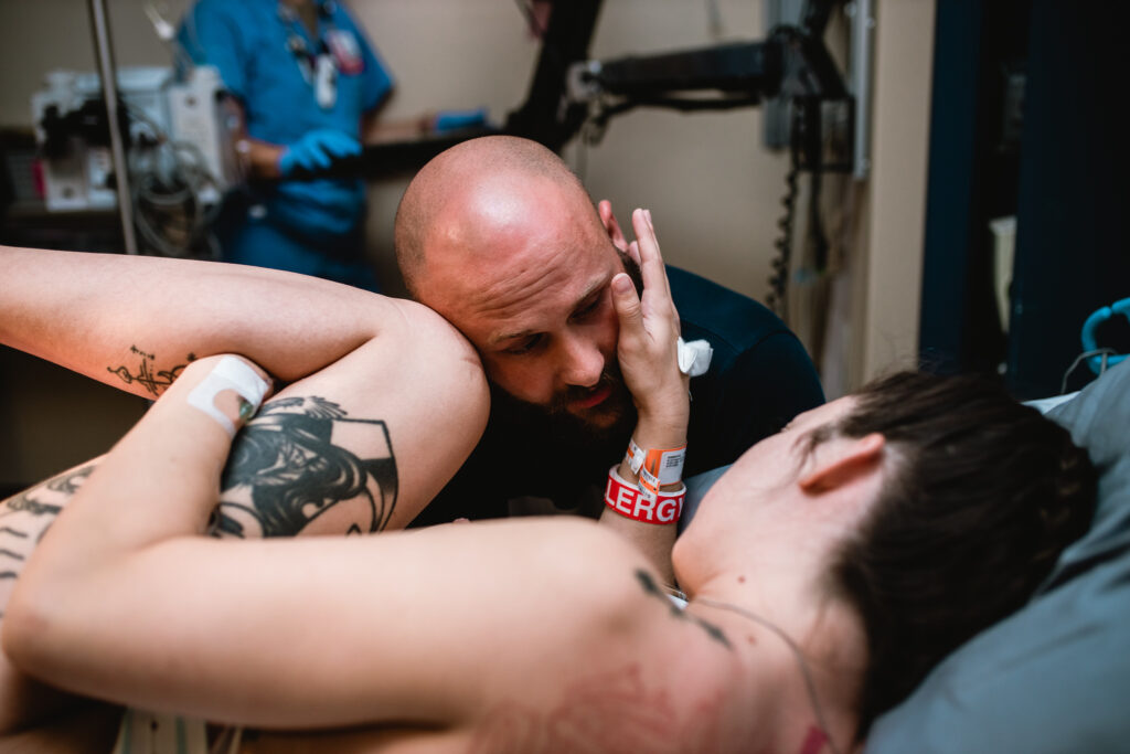 Father supporting mother during labor at a Fort Worth birth, photographed in a documentary storytelling style.
