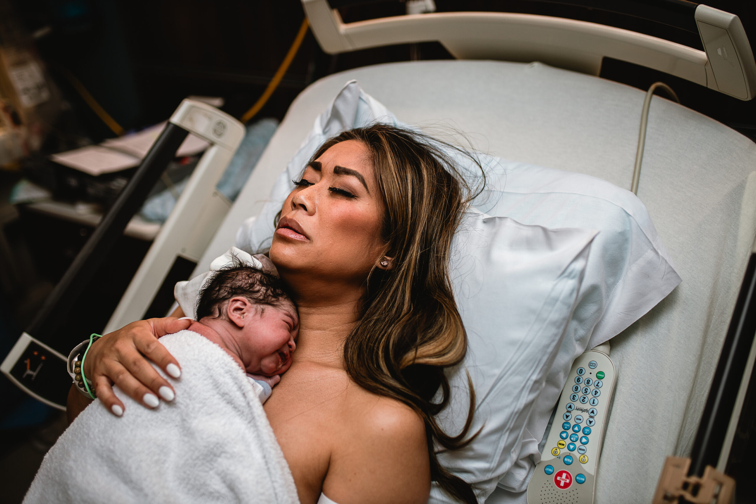 Unposed first hour after birth in Fort Worth, with parents holding their newborn in a quiet and emotional bonding moment documented in a documentary birth photography style.