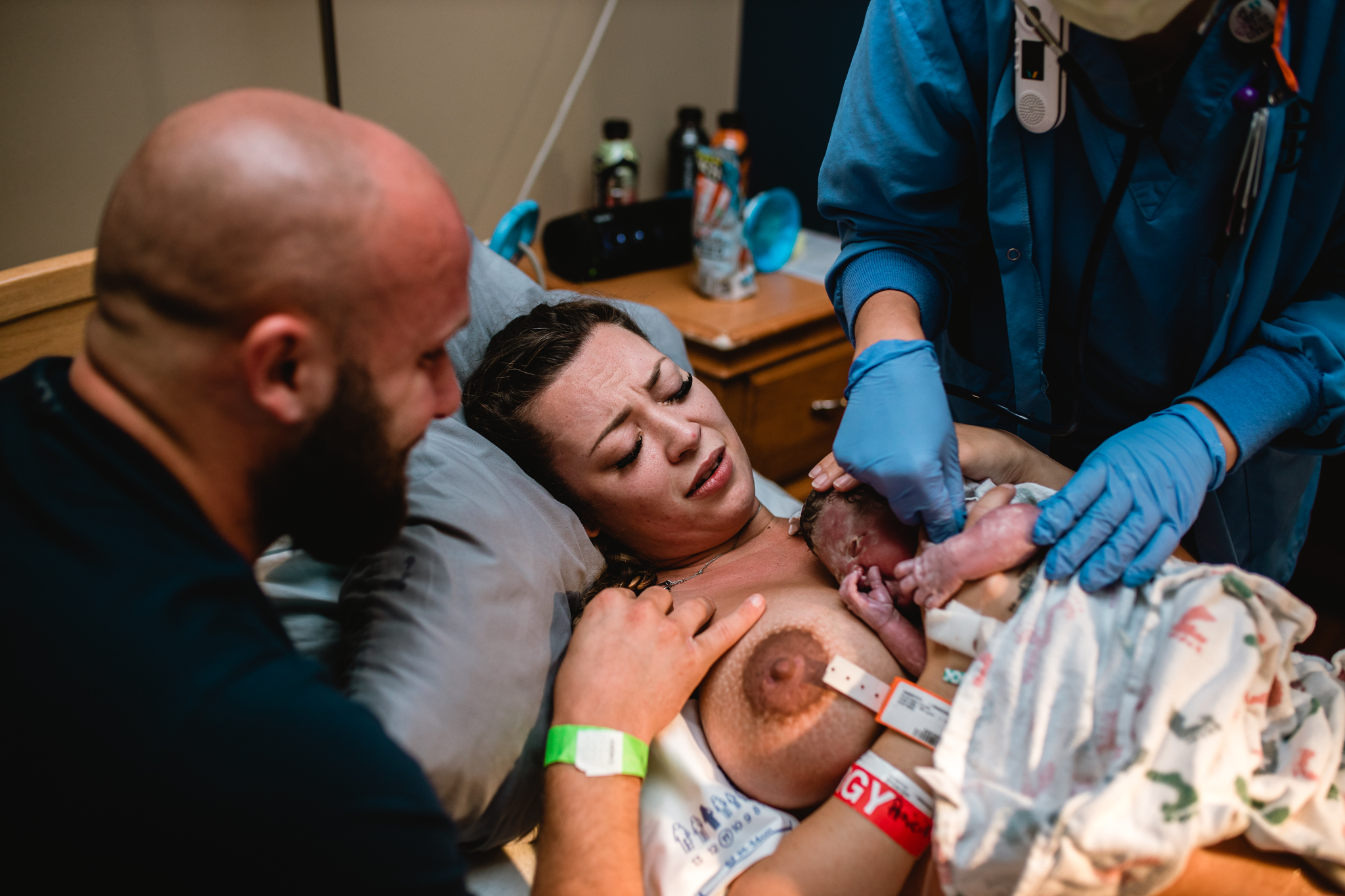 Partner leaning in close as mother holds newborn during birth in Fort Worth, an emotional moment documented by a DFW birth photographer.