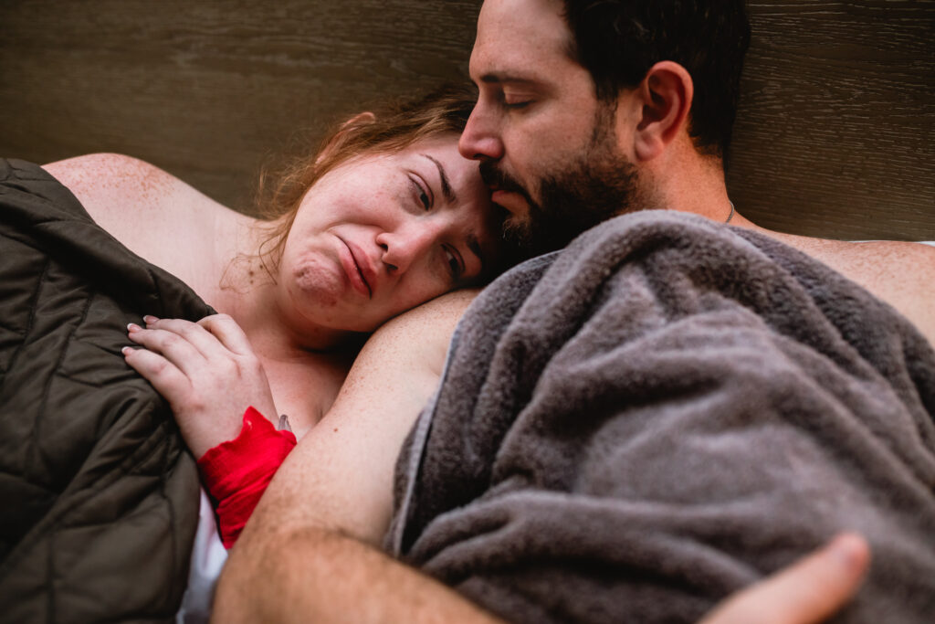 Trauma-informed birth photographer in Fort Worth documenting a calm and emotional moment between a mother, her newborn, and her partner.
