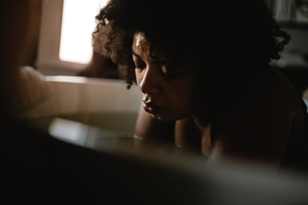 Mother rests between contractions while laboring in the tub, eyes closed and breathing deeply