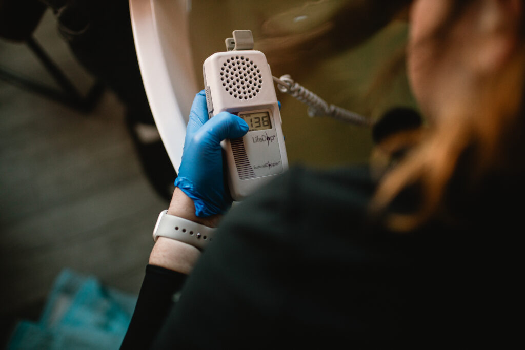 Midwife using a handheld doppler to check baby’s heartbeat during labor in the birth tub