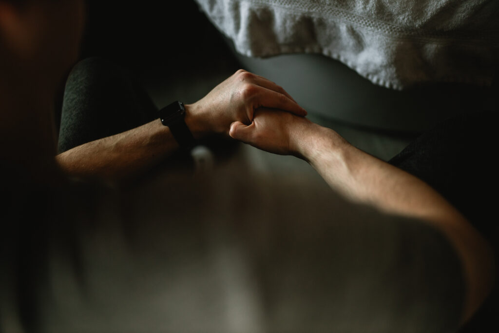 Hands intertwined — husband grounding his wife with touch as she labors