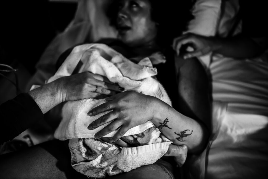 Black and white photo of the mother cradling her newborn in her arms moments after birth