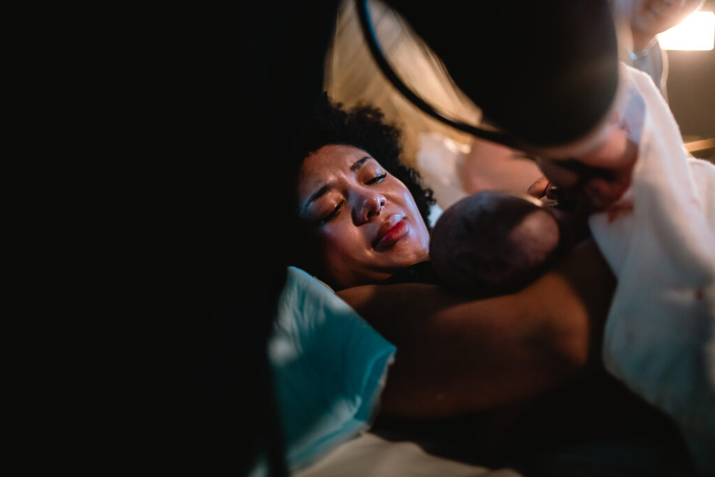 Mother gazing down at her baby while resting in the soft quiet moments after birth