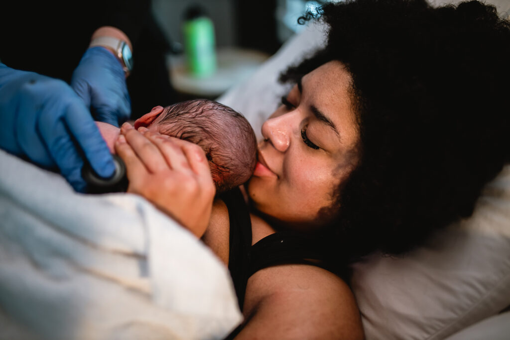 Mother closing her eyes and breathing deeply while cuddling her newborn baby against her chest