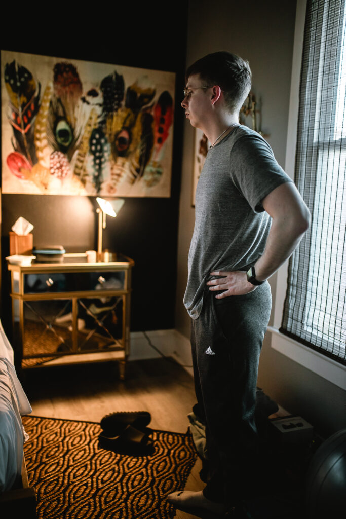 Father standing at the side of the birth center room, watching quietly and processing the moment after birth