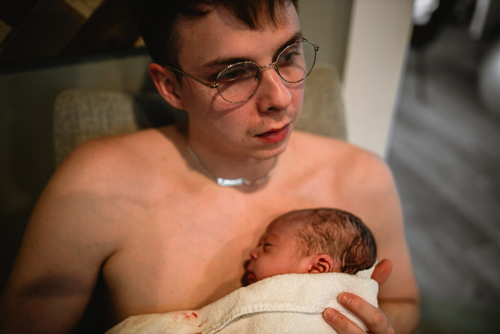 Father holding his newborn baby against his bare chest for skin-to-skin bonding