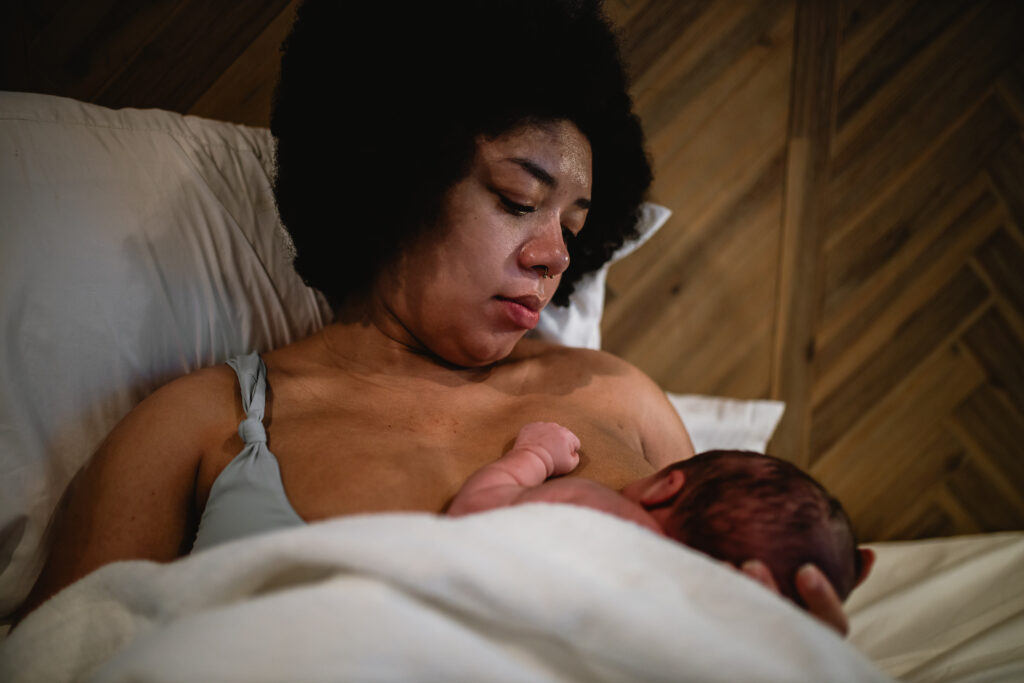 Mother resting in bed with her newborn on her chest during the first hour after birth