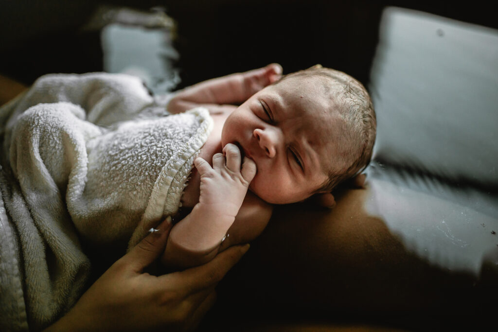 Close-up of newborn wrapped in a soft blanket, eyes open and alert