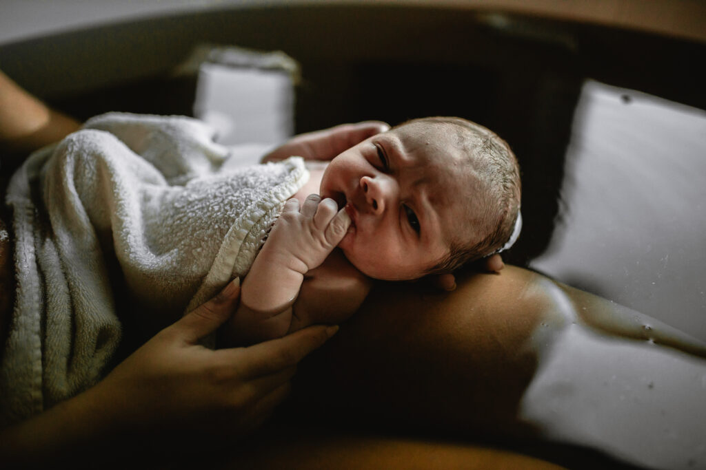 Newborn resting on mother’s chest while sunlight falls across their face