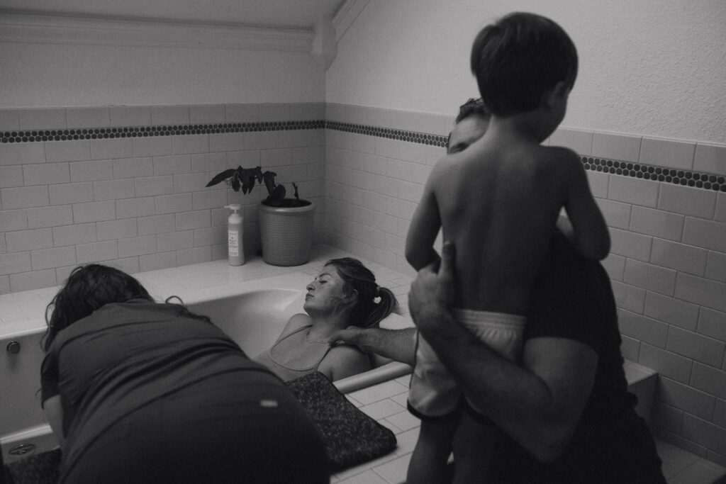 Documentary home birth — older sibling present while mother labors in bathtub