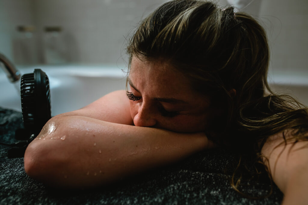 Mother breathing through contraction while resting on edge of birth tub
