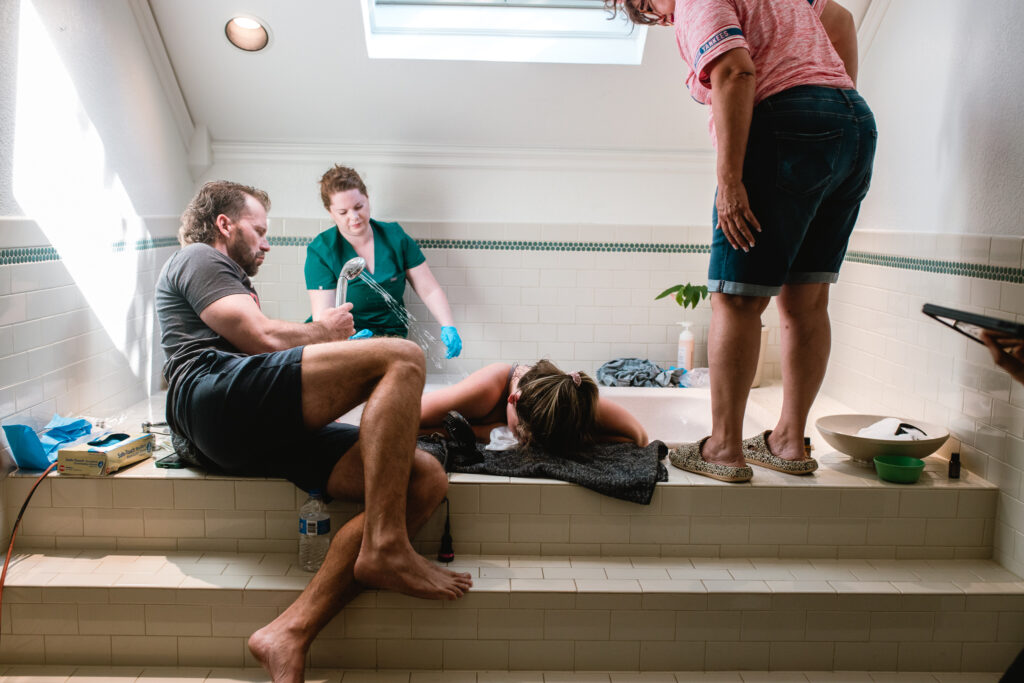 Midwife preparing birth supplies beside bathtub during home birth