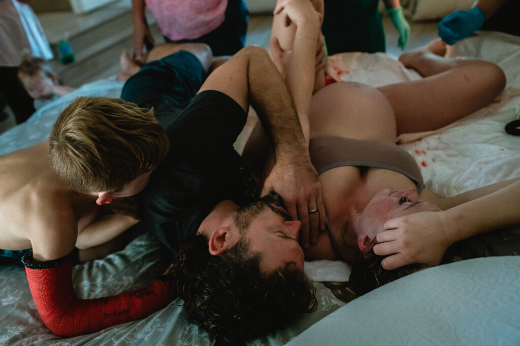 Big brother snuggled close to his mother as they soak in newborn moments