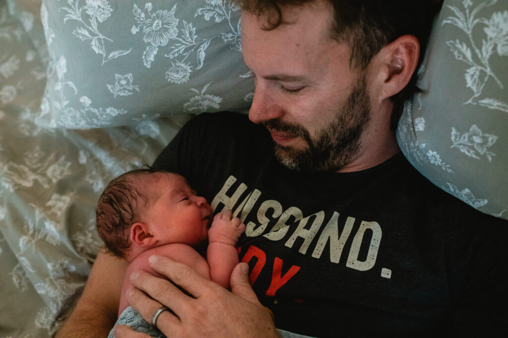 Father holding newborn on his chest during quiet bonding moments after home birth
