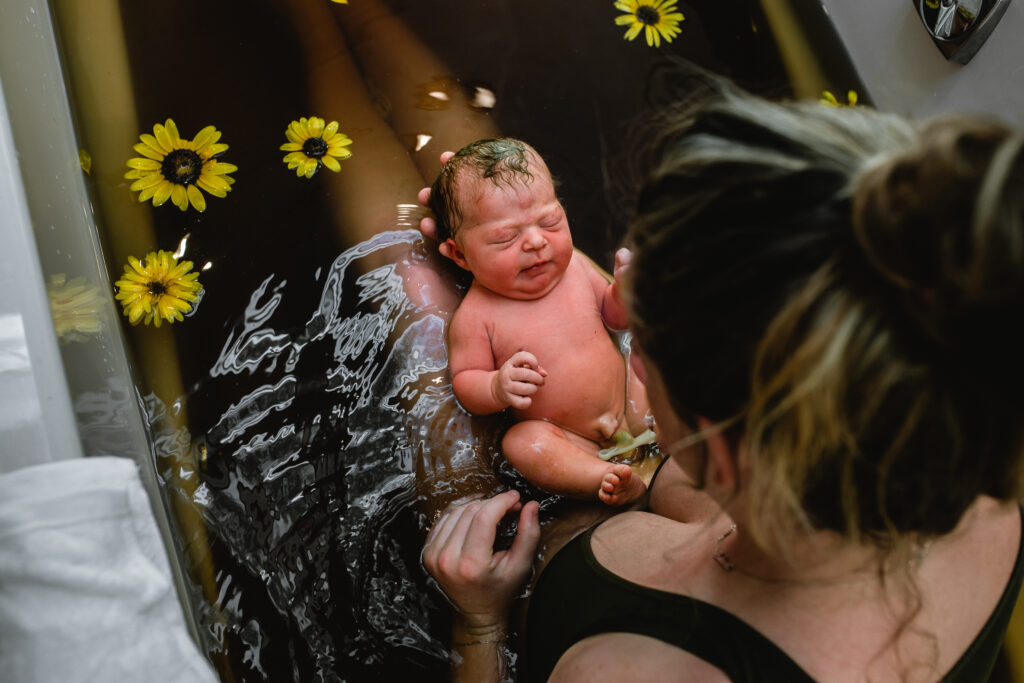 Father wiping tears while cradling newborn baby after emotional home birth