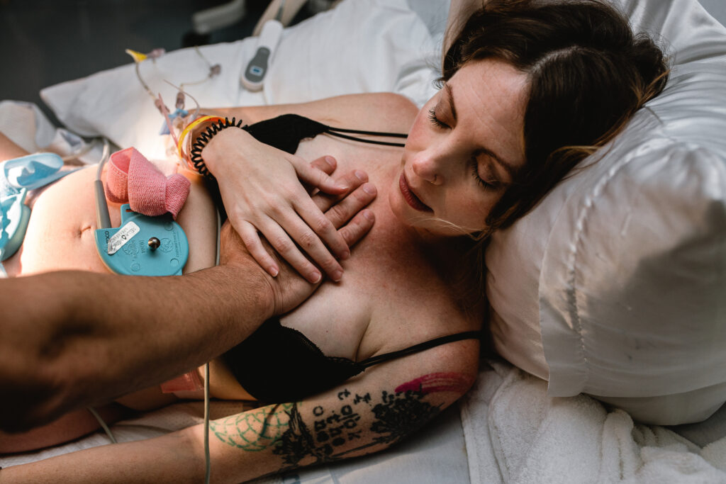 Mother resting between contractions with her husband’s hand on her chest for comfort and reassurance
