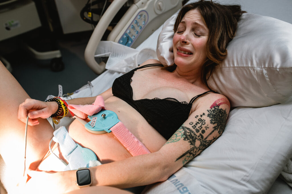 Mother working through a powerful contraction while laboring in a hospital bed during second stage of labor