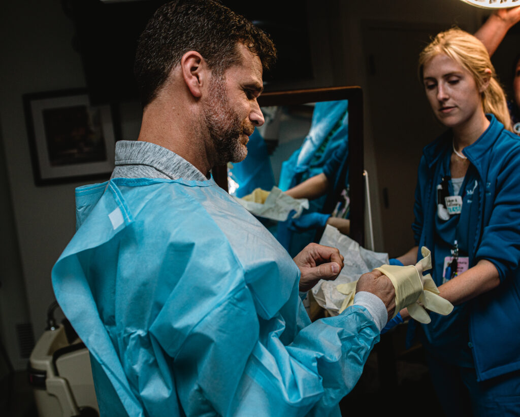 Expectant father putting on sterile gloves while preparing to help catch his baby during hospital birth