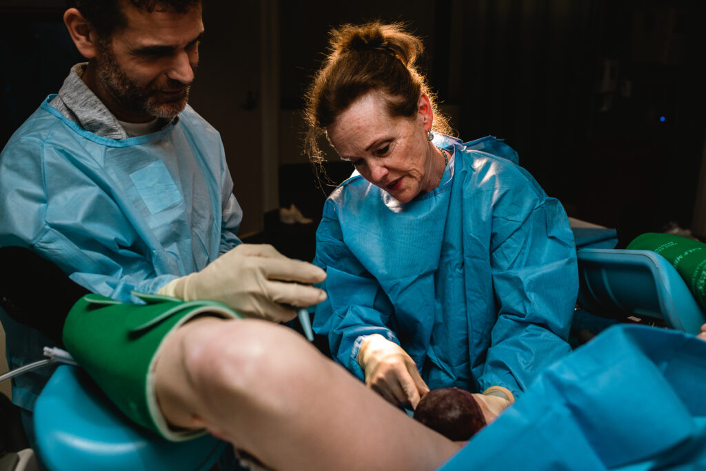 Mother gripping the sheet and pushing with strength and determination while her husband supports her