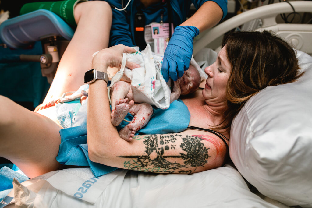 Parents holding their newborn baby together under the warm delivery room lights after a successful hospital birth