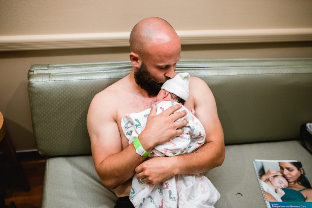 Emotional moment of a partner meeting their newborn for the first time in Fort Worth, captured in a documentary birth photography style.