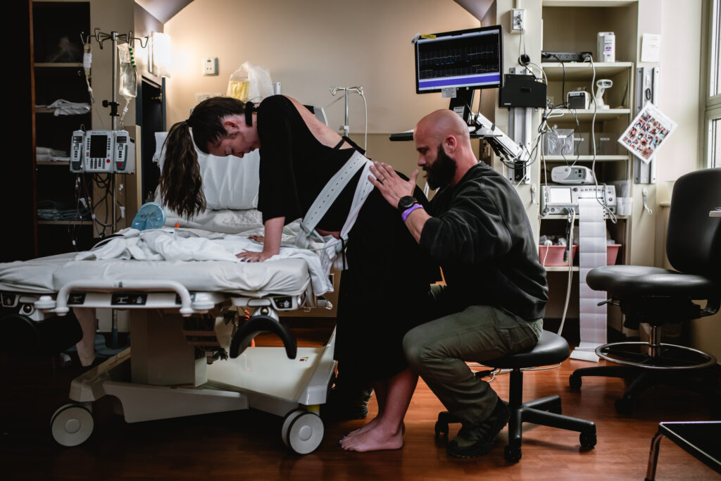 Mother leaning through a contraction while her partner quietly supports her during labor.